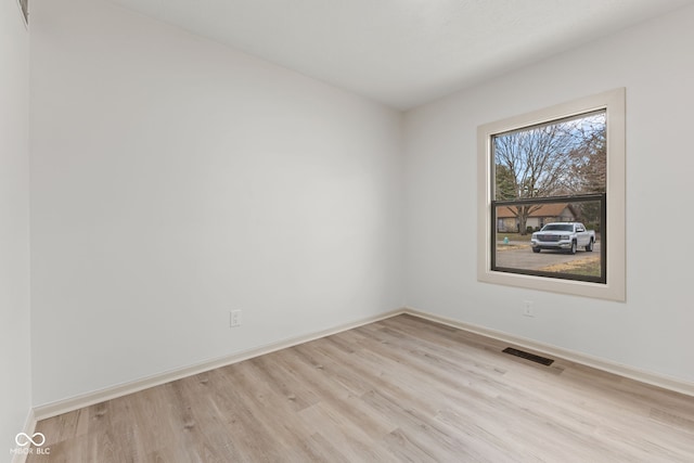 spare room featuring visible vents, baseboards, and wood finished floors