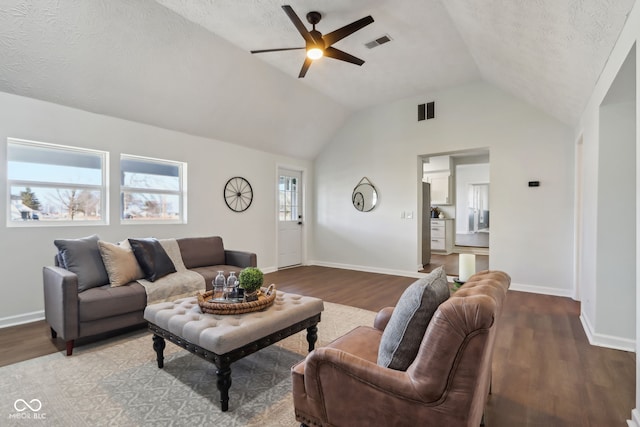 living area with visible vents, a textured ceiling, wood finished floors, and vaulted ceiling