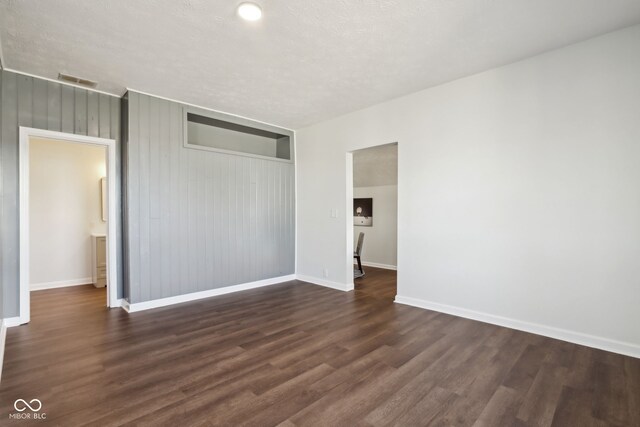 unfurnished bedroom with visible vents, a textured ceiling, a closet, baseboards, and dark wood-style flooring