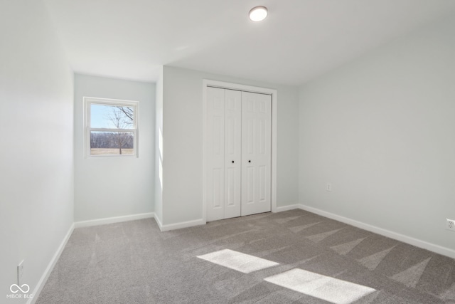 unfurnished bedroom featuring baseboards, carpet floors, and a closet