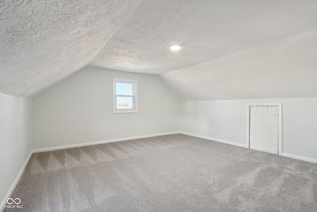 bonus room featuring vaulted ceiling, carpet, baseboards, and a textured ceiling