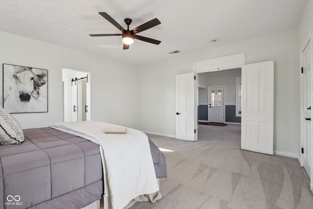 bedroom with visible vents, light colored carpet, baseboards, and ceiling fan