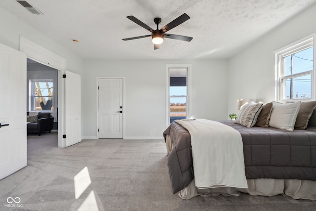 bedroom featuring light carpet, visible vents, multiple windows, and a textured ceiling