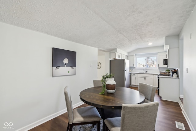 dining area featuring baseboards, a textured ceiling, and dark wood finished floors