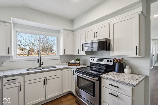 kitchen featuring light stone countertops, dark wood finished floors, white cabinets, stainless steel appliances, and a sink