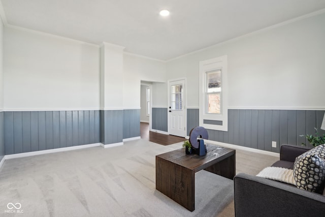 living room featuring crown molding, a wainscoted wall, and carpet floors