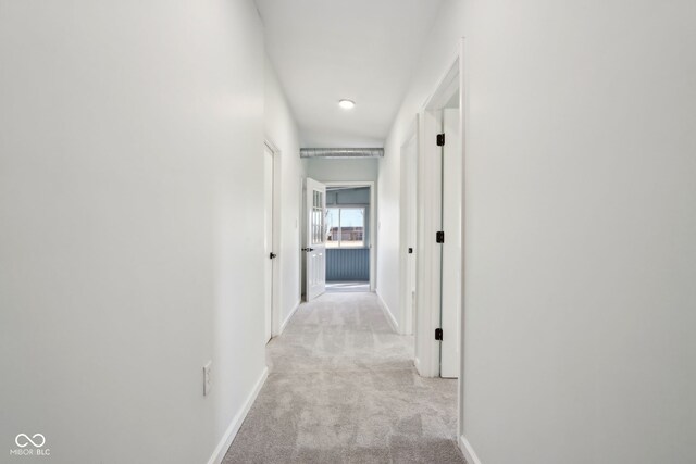 hallway with light colored carpet and baseboards