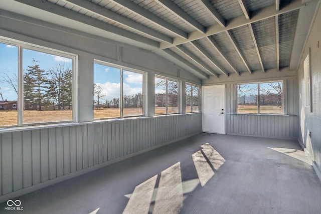 unfurnished sunroom featuring lofted ceiling with beams