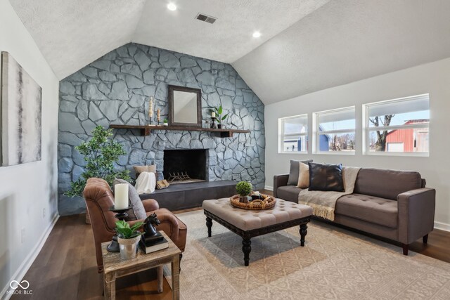 living area featuring a stone fireplace, lofted ceiling, wood finished floors, and visible vents