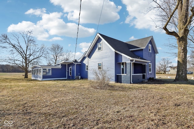 view of side of home featuring cooling unit, a lawn, brick siding, and a sunroom