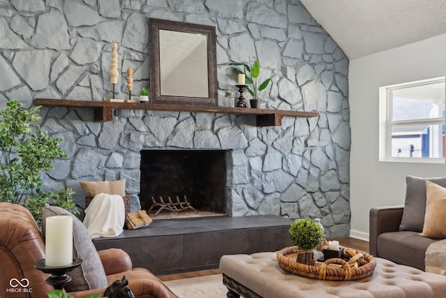 living area with a stone fireplace, lofted ceiling, wood finished floors, and a textured ceiling