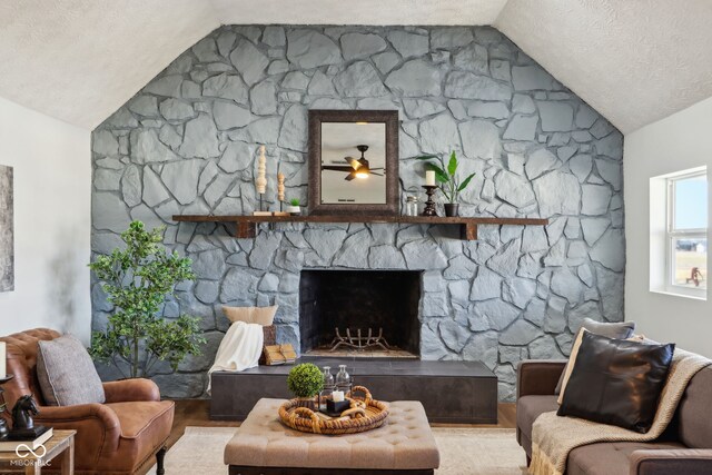 living room with a textured ceiling, a fireplace, and vaulted ceiling