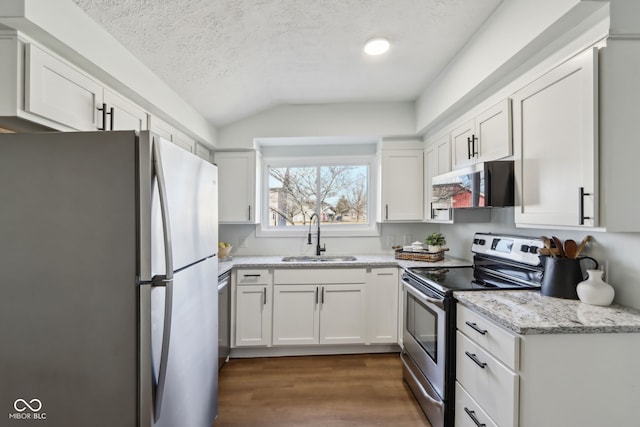 kitchen with range hood, dark wood finished floors, a sink, appliances with stainless steel finishes, and white cabinetry