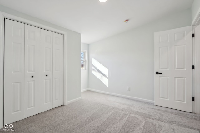 unfurnished bedroom with carpet flooring, baseboards, and a closet