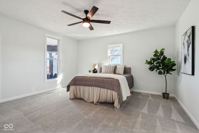 carpeted bedroom with visible vents, baseboards, a textured ceiling, and ceiling fan