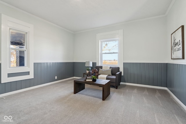 living area with carpet flooring, wainscoting, visible vents, and ornamental molding