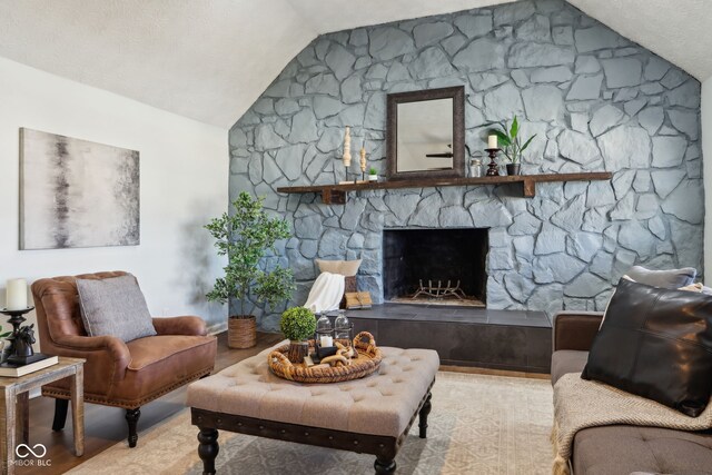 living room with a fireplace, a textured ceiling, and lofted ceiling