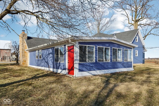 exterior space with a yard, a chimney, and a shingled roof