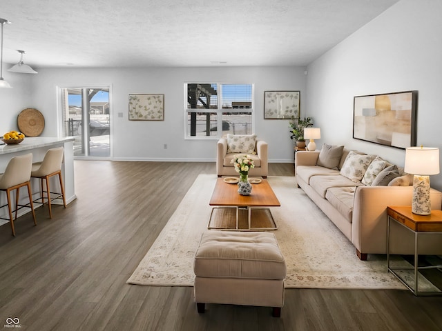 living room with dark wood finished floors, a textured ceiling, and baseboards