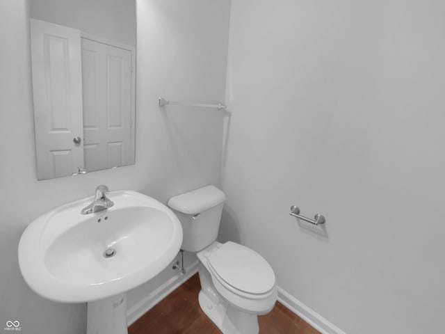 bathroom with toilet, baseboards, and a sink