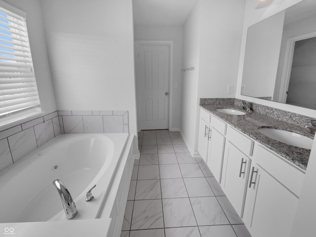 bathroom featuring a bath, marble finish floor, double vanity, and a sink