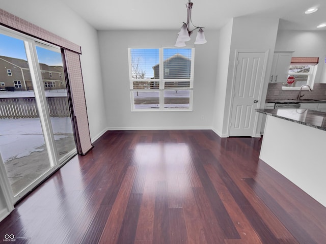 unfurnished dining area with dark wood finished floors, recessed lighting, baseboards, and a sink