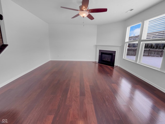 unfurnished living room with a glass covered fireplace, baseboards, and wood finished floors