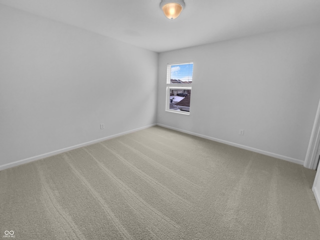 unfurnished room with light colored carpet and baseboards