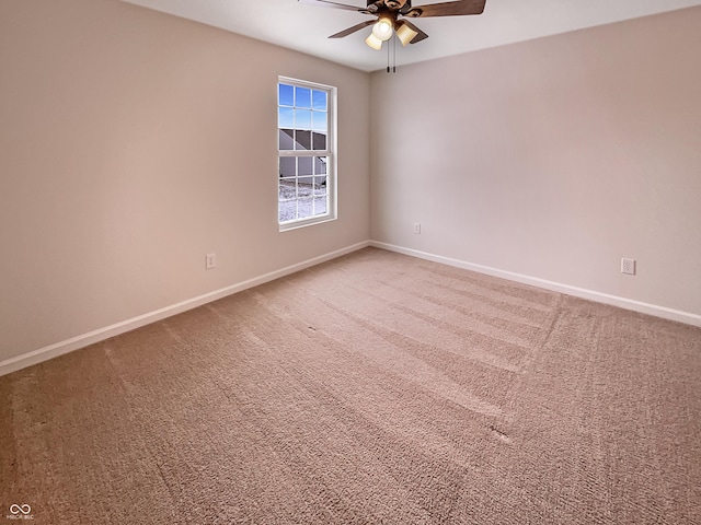 carpeted spare room with ceiling fan and baseboards