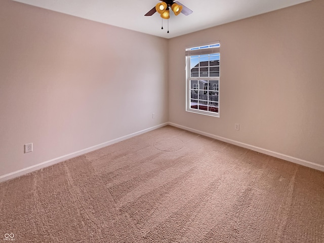 empty room featuring a ceiling fan, light colored carpet, and baseboards