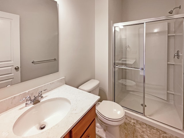 bathroom with a stall shower, toilet, and vanity