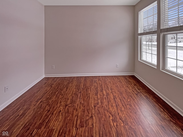 spare room featuring dark wood finished floors and baseboards