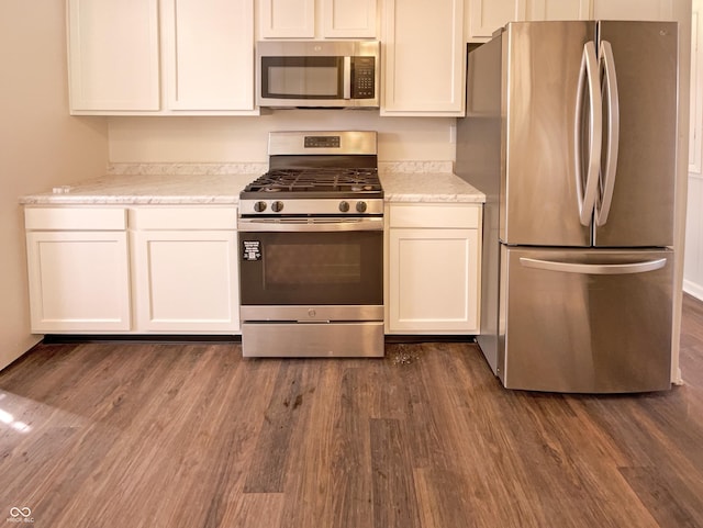 kitchen with dark wood-style floors, white cabinetry, stainless steel appliances, and light stone counters