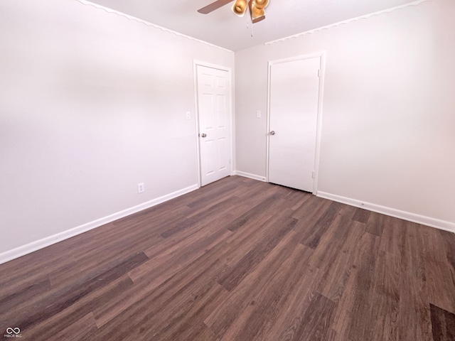 unfurnished room with baseboards, dark wood-style floors, and a ceiling fan