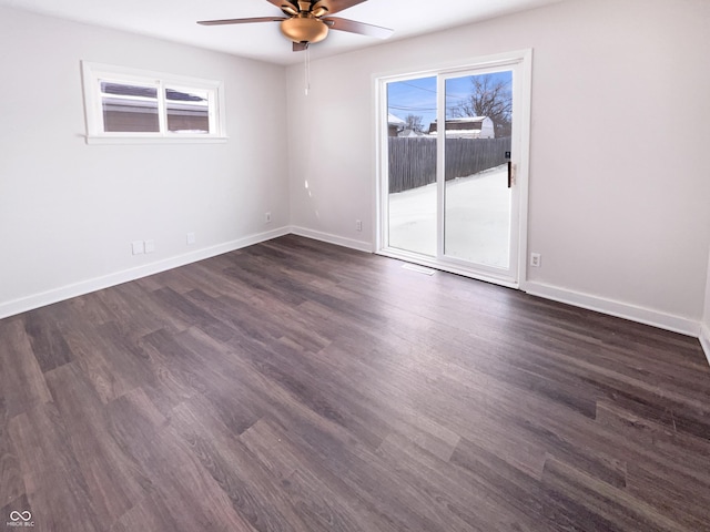 unfurnished room featuring a wealth of natural light, dark wood-style floors, ceiling fan, and baseboards