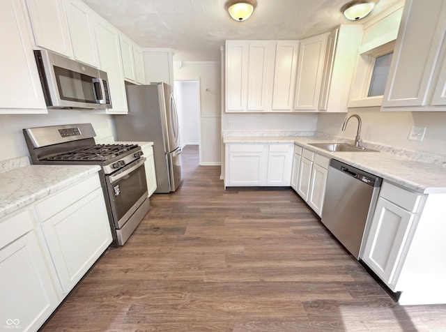 kitchen with a sink, appliances with stainless steel finishes, dark wood-style floors, and white cabinetry