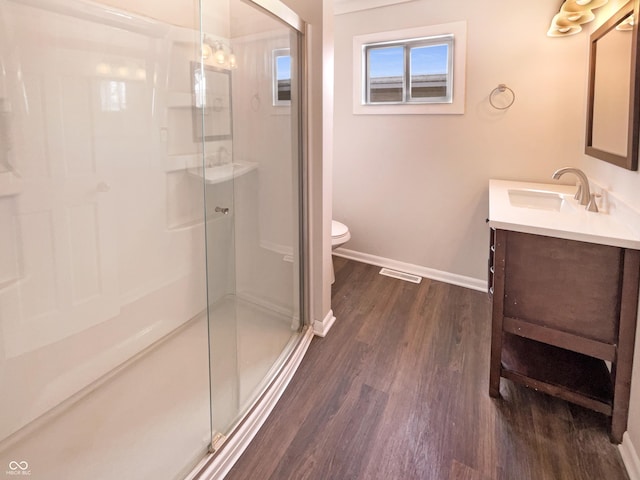 bathroom with baseboards, wood finished floors, a stall shower, and vanity