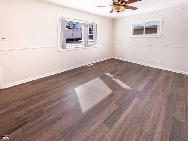 spare room featuring a ceiling fan, wainscoting, and dark wood-style flooring