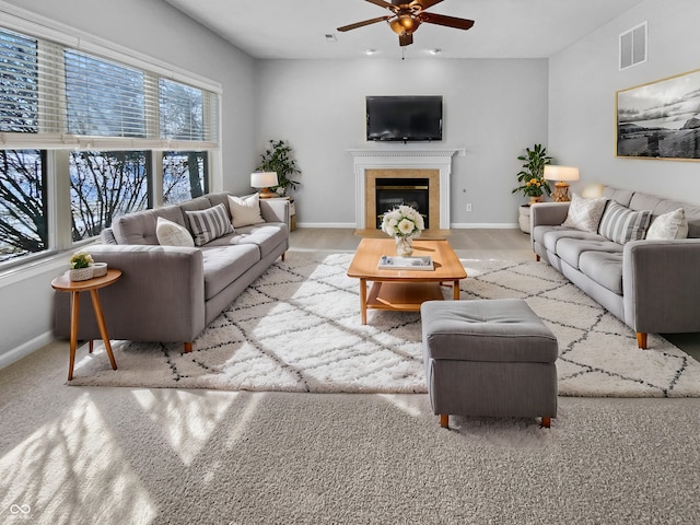 living area with visible vents, baseboards, a ceiling fan, and a tile fireplace