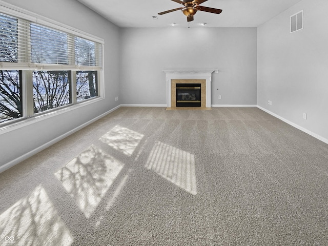 unfurnished living room with visible vents, ceiling fan, baseboards, a tiled fireplace, and carpet floors