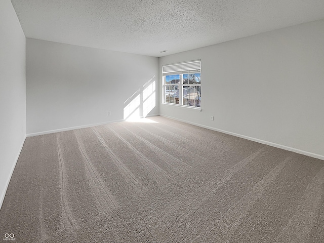 carpeted spare room with baseboards and a textured ceiling