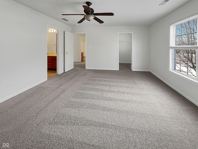 unfurnished bedroom featuring carpet, visible vents, baseboards, a closet, and a walk in closet