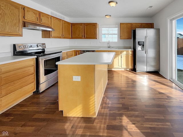 kitchen featuring dark wood finished floors, a sink, stainless steel appliances, light countertops, and under cabinet range hood