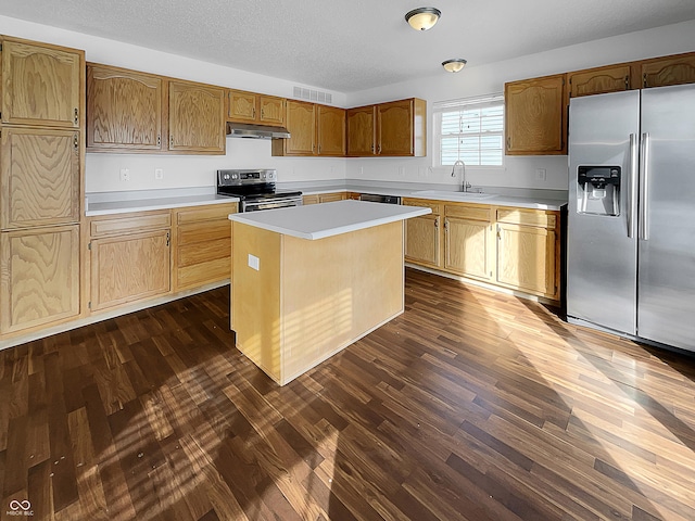 kitchen with dark wood-type flooring, a sink, under cabinet range hood, appliances with stainless steel finishes, and light countertops