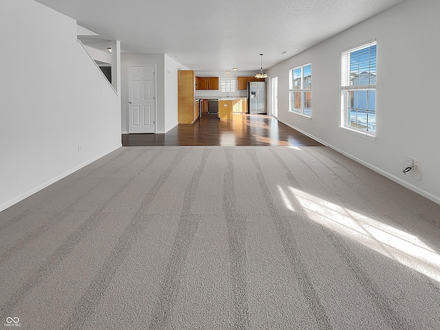 unfurnished living room featuring dark wood finished floors, baseboards, and dark carpet