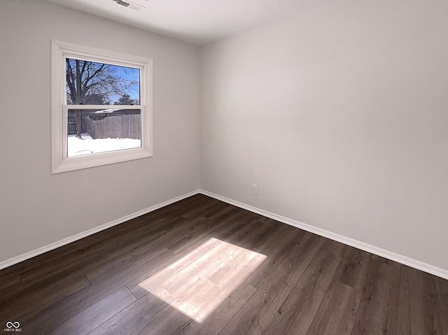 spare room featuring dark wood-style floors, visible vents, and baseboards