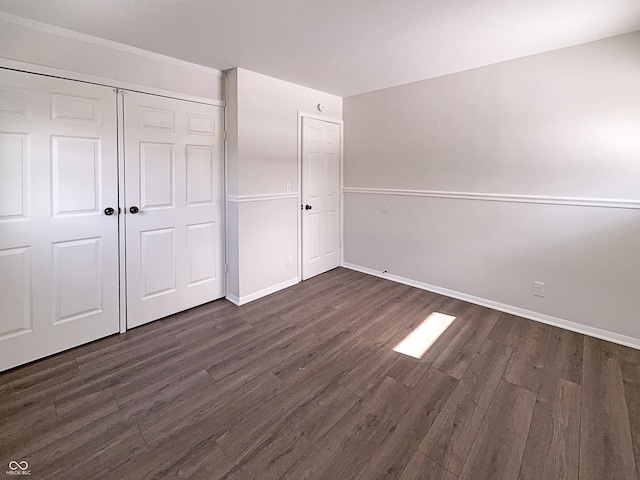 unfurnished bedroom with dark wood-type flooring, baseboards, and a closet