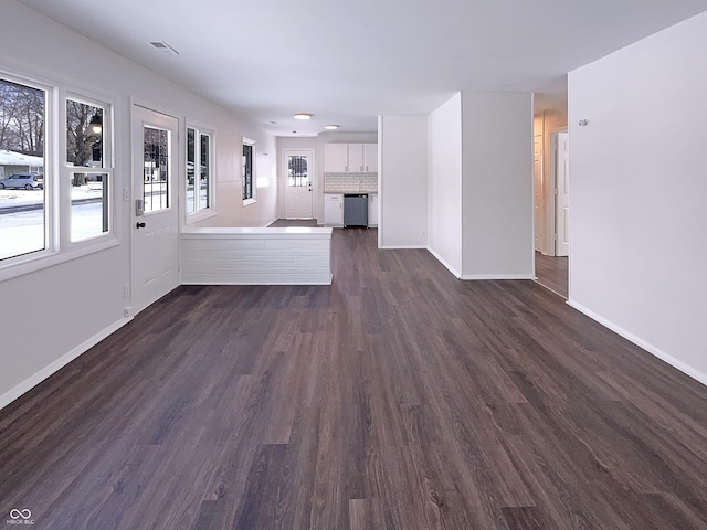 unfurnished living room featuring dark wood finished floors, visible vents, and baseboards