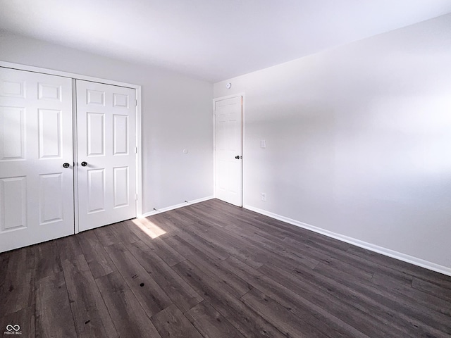 unfurnished bedroom featuring dark wood-type flooring, baseboards, and a closet