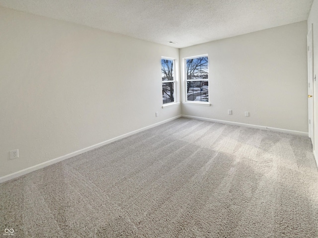 carpeted empty room featuring a textured ceiling and baseboards